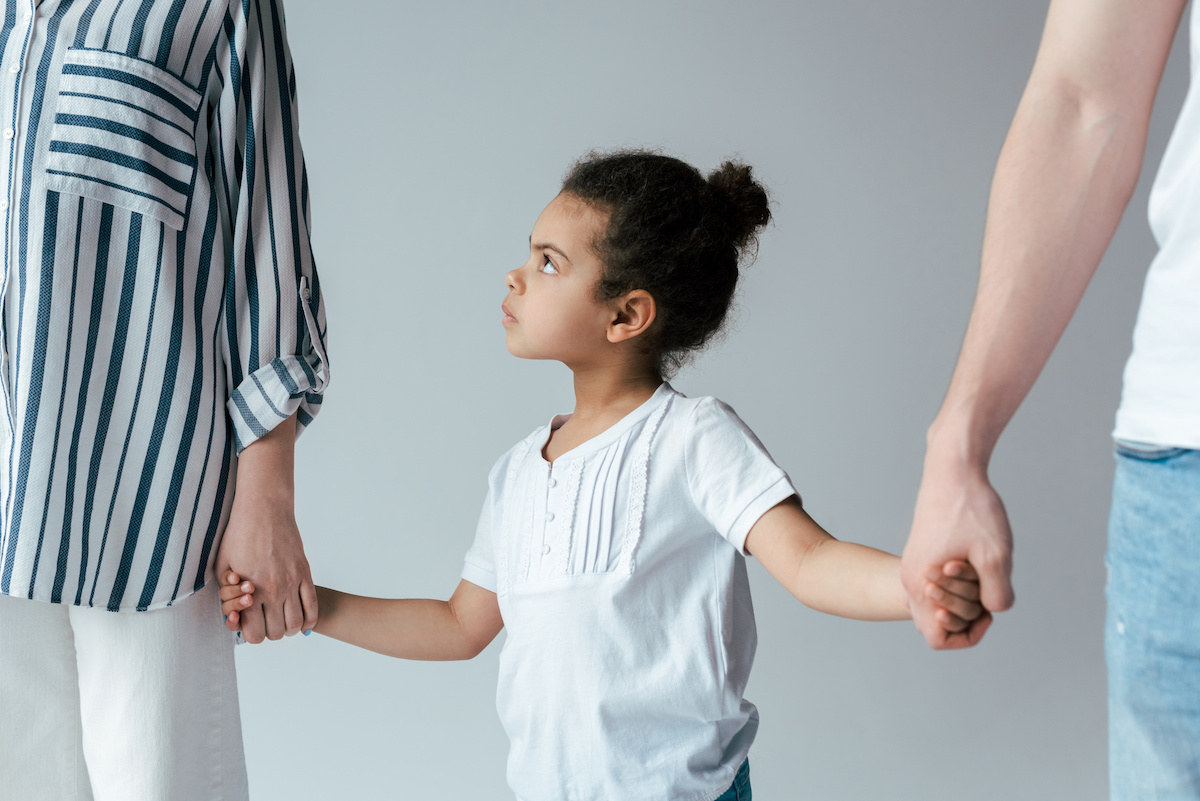 sad african american kid holding hands with divorced foster parents isolated