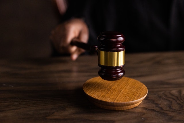 Judge poised to tap a gavel on the desk, symbolizing the moment of judicial decision-making in a courtroom.