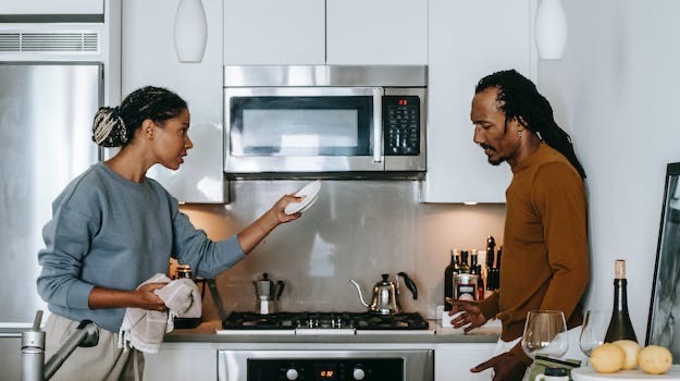 Man and woman discussing amicably in a kitchen setting, exemplifying collaborative divorce communication.
