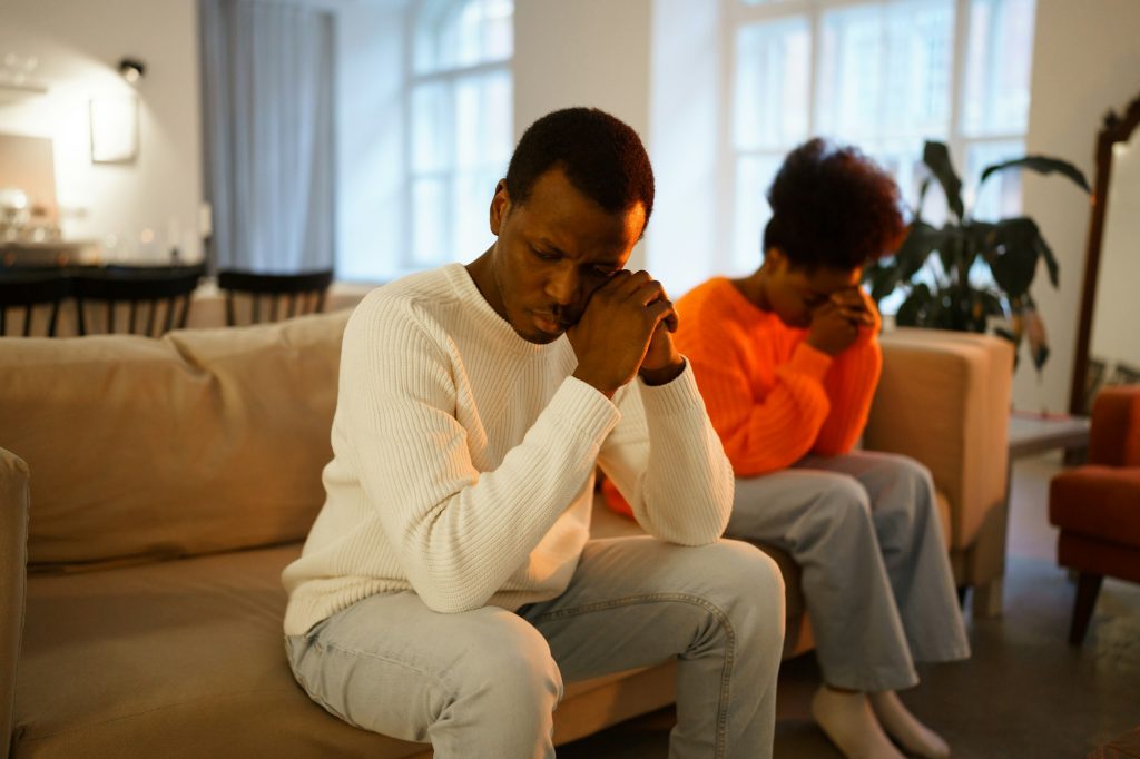 Family conflict. Unhappy african couple sit separate on couch upset thinking of breakup or divorce